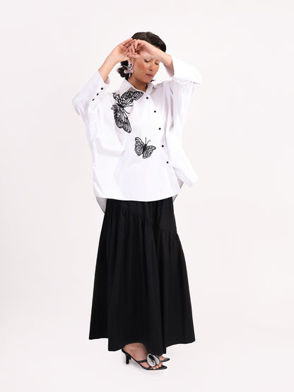 Woman wearing a white blouse with butterfly patterns and a black skirt on a white background